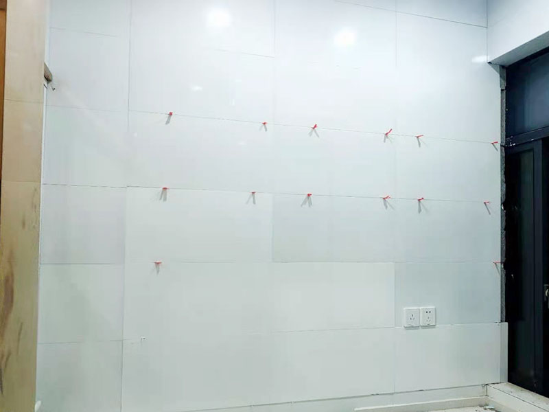 墻磚鋪貼施工：基層處理：保持墻面的平滑，踢平表面凹凸不平的位置或用1:3比例的水泥漿抹平，用鐵絲擦掉殘留的灰塵、油漬、砂漿等。 找標高、彈線：根據水平控制線和設計圖紙劃出標高，再拋出十字線并保持墻面一線和地面一線垂直。 預鋪：在圖紙設計要求的基礎上，嚴格挑選墻磚的色彩、紋理等，然后進行預鋪，對于預鋪效果中可能出現的紋理、尺寸、色差進行調整、更換，直到達到最佳效果。 貼磚：貼磚選用1：3比例的干硬性水泥砂漿，砂漿厚度2cm左右。鋪貼前將墻磚背面濕潤，正面保持干燥。把墻磚輕輕地放在水泥砂漿上，用手錘輕敲瓷磚表面直至緊密平整即可。 勾縫、擦縫：在貼完磚24小時后進行勾縫工作，采用同一品種的水泥漿或專用填縫劑進行空隙填補，使墻磚最終緊密嚴實，最后再擦凈多余的水泥或填縫劑。